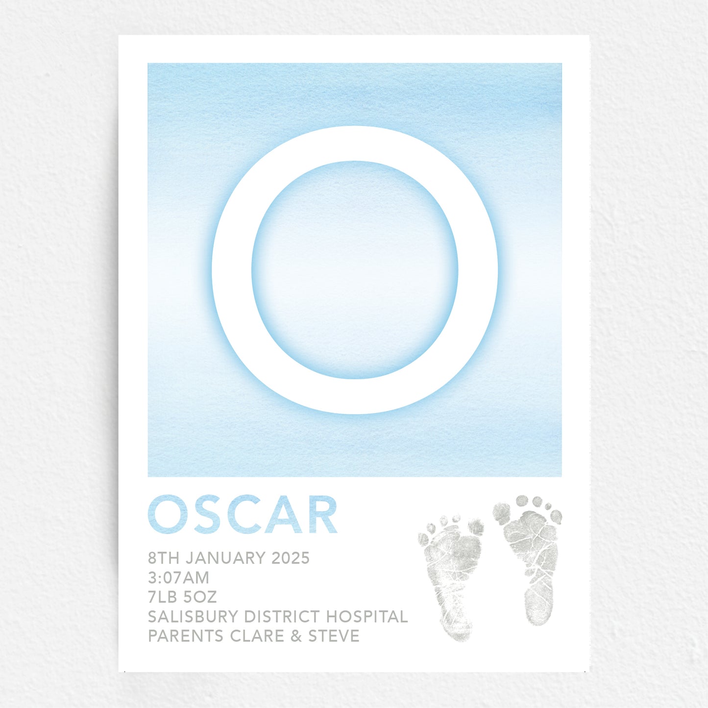 A personalised baby print with the initial 'O' in large blue lettering, birth details, and baby feet prints.
