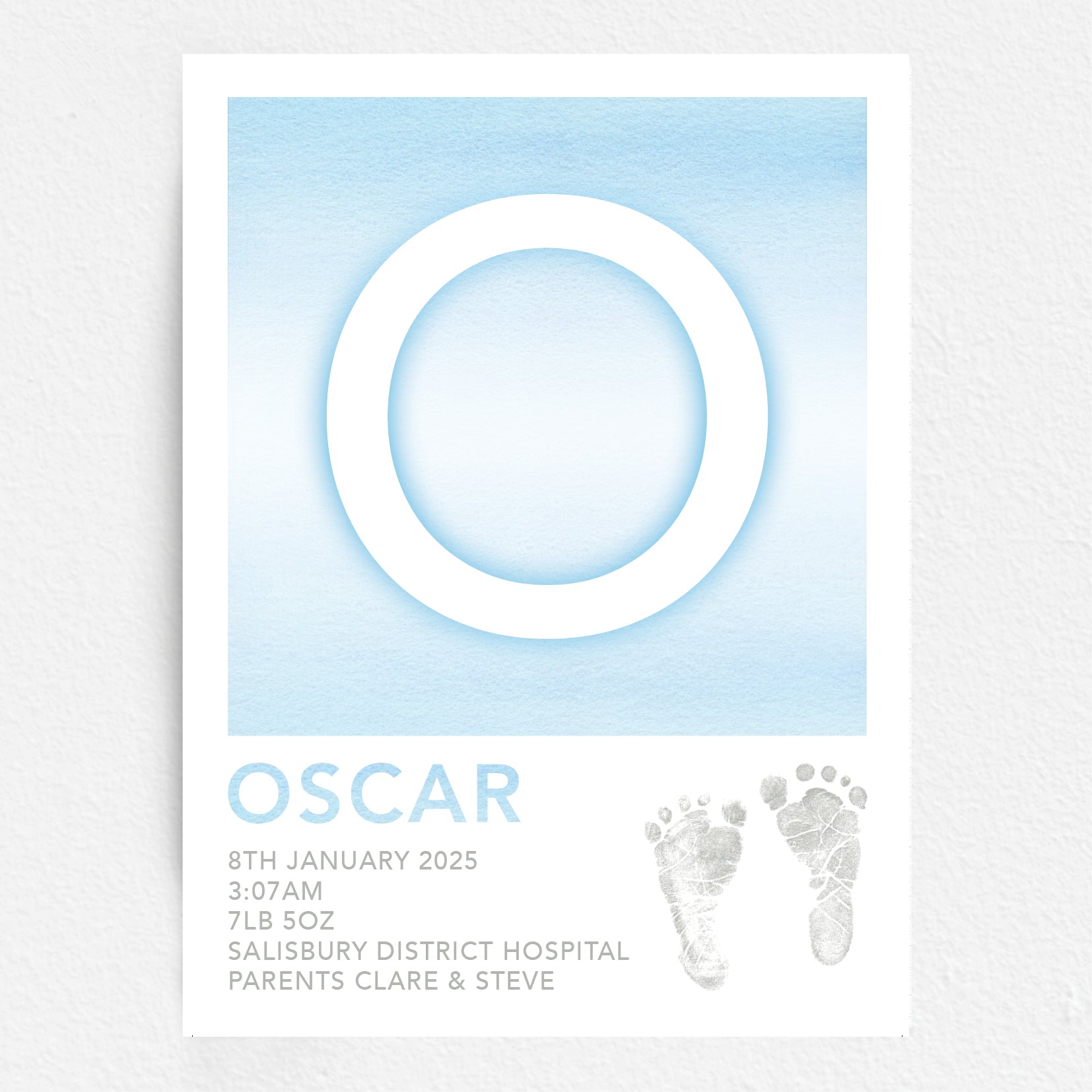 A personalised baby print with the initial 'O' in large blue lettering, birth details, and baby feet prints.