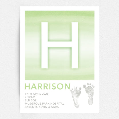 A personalised baby print with the initial 'H' in large green lettering, birth details, and baby feet prints.