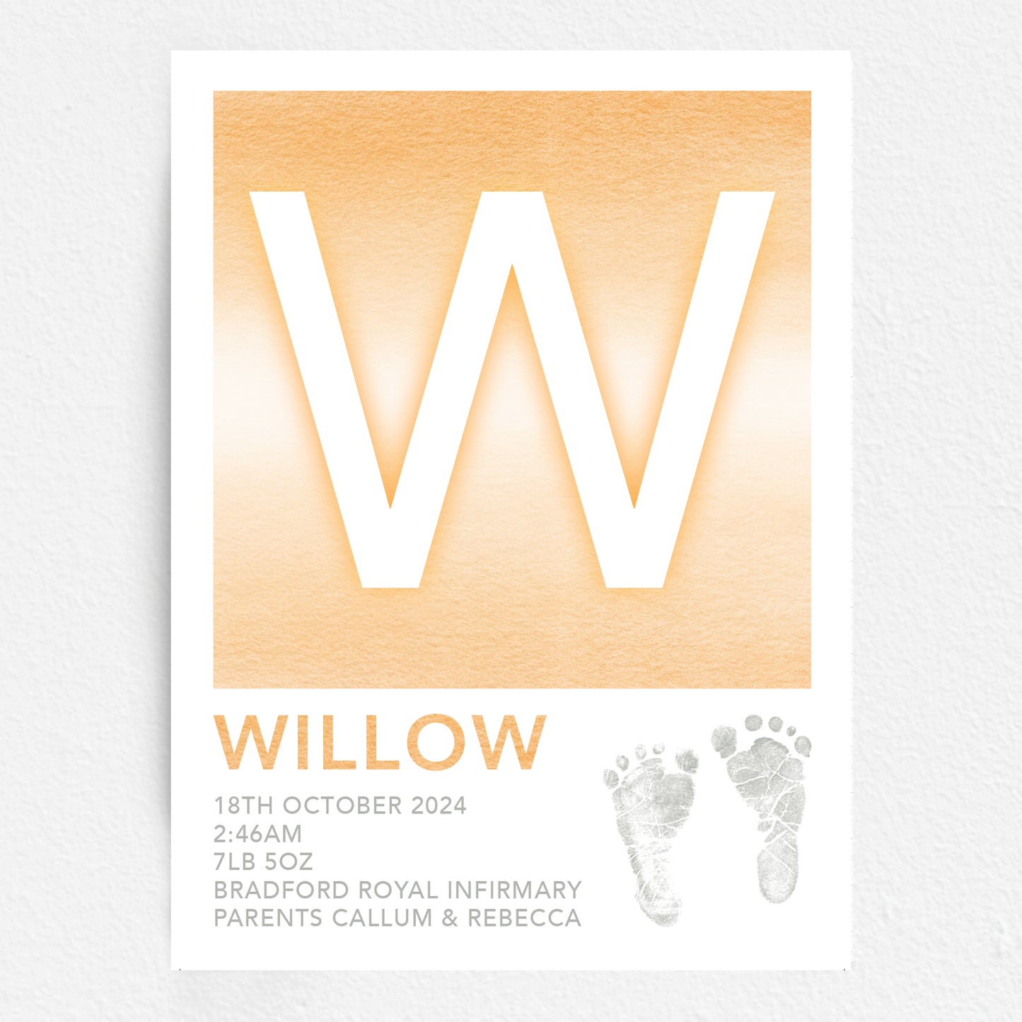 A personalised baby print with the initial 'W' in large orange lettering, birth details, and baby feet prints.