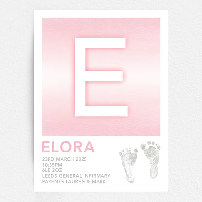 A personalised baby print with the initial 'E' in large pink lettering, birth details, and baby feet prints.
