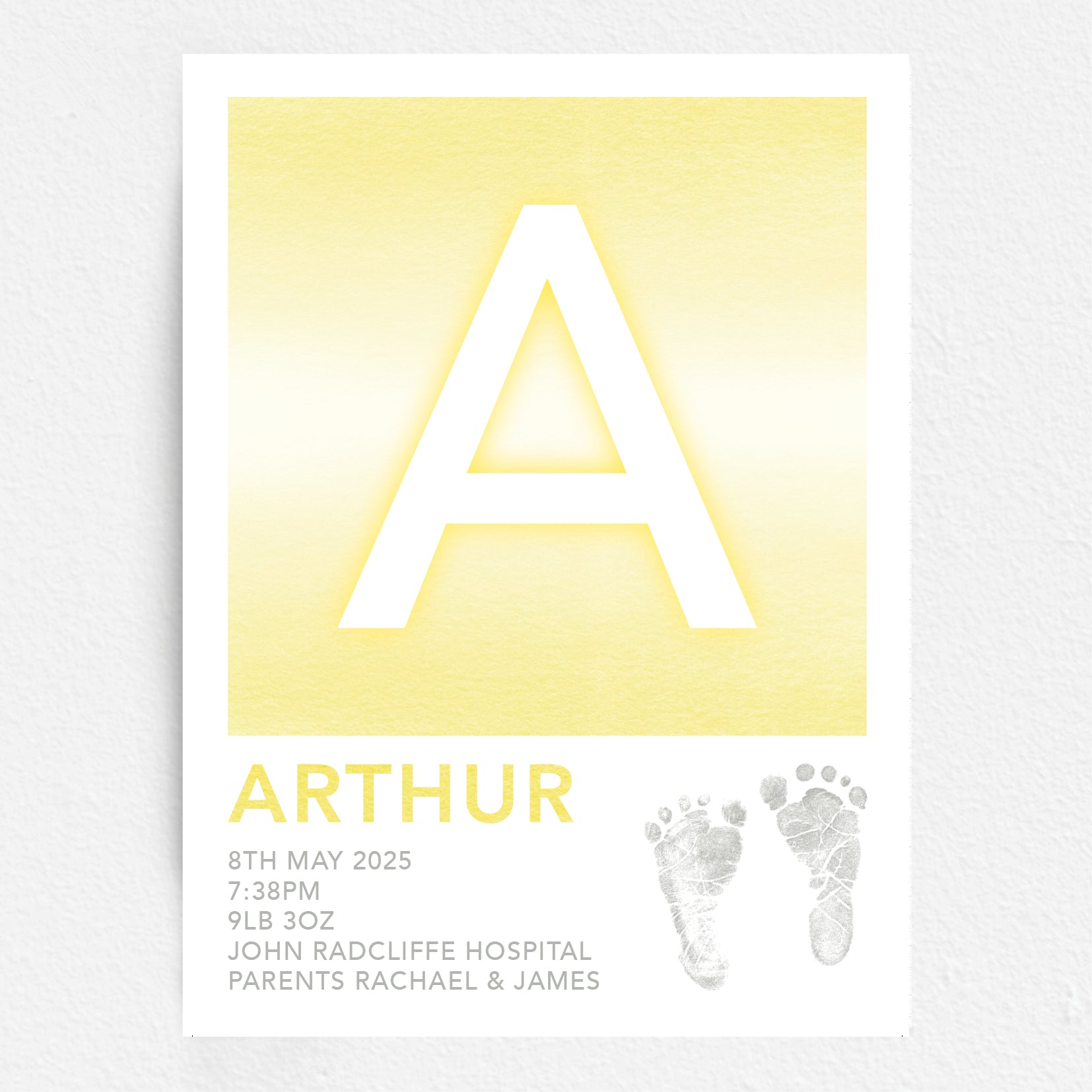 A personalised baby print with the initial 'A' in large yellow lettering, birth details, and baby feet prints.